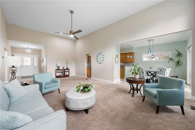 living room featuring baseboards, ceiling fan, and light colored carpet