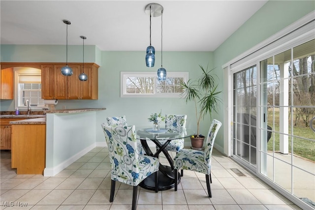 dining room featuring light tile patterned floors, visible vents, baseboards, and a wealth of natural light