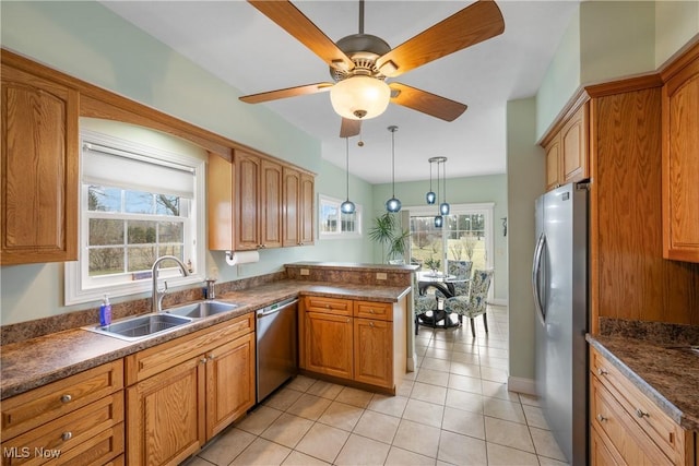 kitchen featuring appliances with stainless steel finishes, dark countertops, a sink, and decorative light fixtures