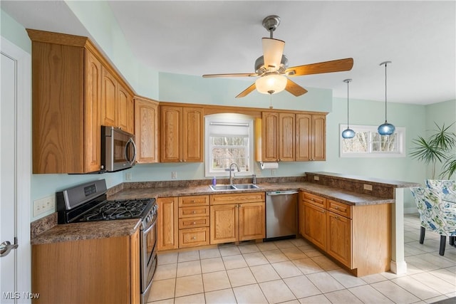 kitchen featuring stainless steel appliances, dark countertops, pendant lighting, and a sink