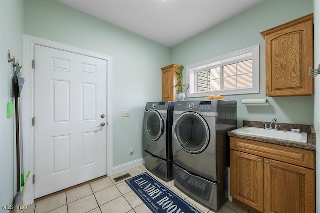 washroom with cabinet space, light tile patterned floors, visible vents, washer and dryer, and a sink