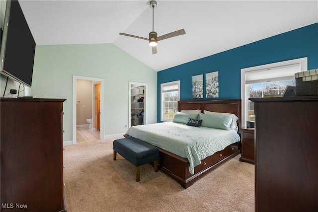 bedroom with light colored carpet, a spacious closet, connected bathroom, vaulted ceiling, and baseboards