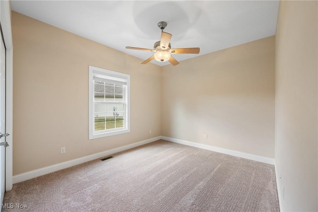 spare room with baseboards, visible vents, ceiling fan, and light colored carpet