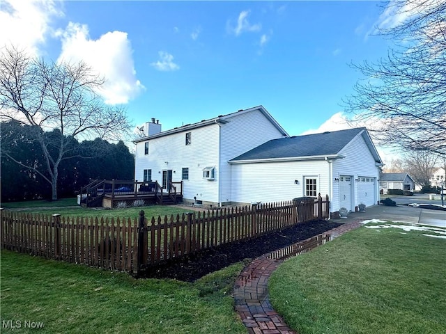 back of house with a garage, a fenced front yard, a chimney, and a deck