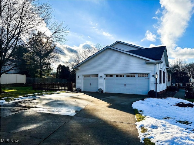 view of side of property featuring a garage, fence, and concrete driveway