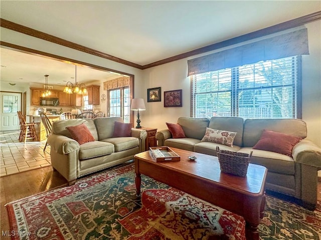 living area with a notable chandelier, wood finished floors, and crown molding