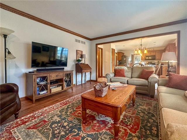 living room with baseboards, visible vents, ornamental molding, dark wood-style flooring, and an inviting chandelier