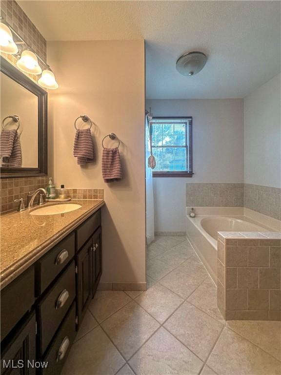 bathroom featuring tasteful backsplash, baseboards, a garden tub, tile patterned flooring, and vanity