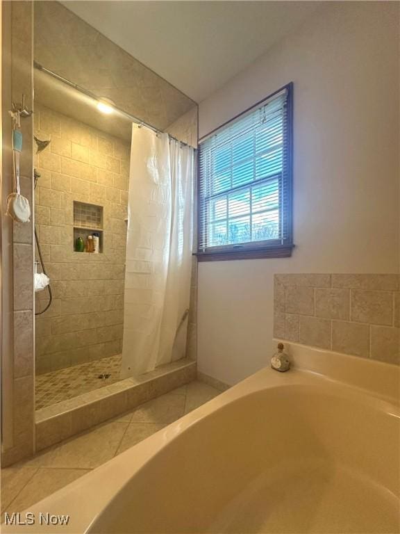 bathroom featuring a stall shower, a garden tub, and tile patterned floors