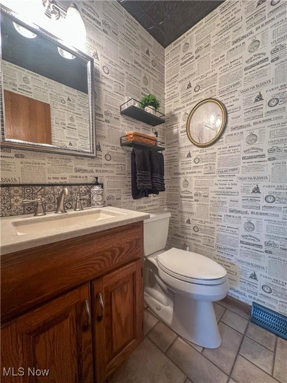 bathroom with toilet, vanity, and tile patterned floors