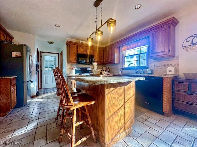 kitchen featuring a center island, light countertops, stone tile floors, and black appliances