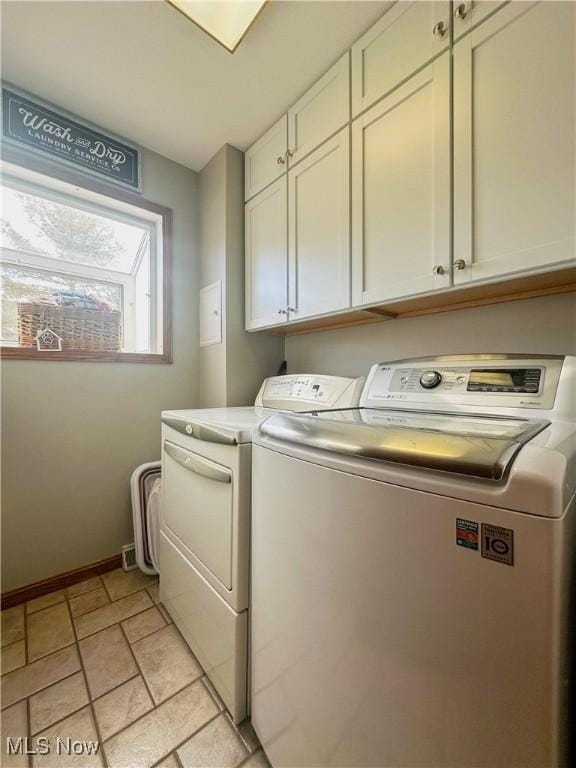 clothes washing area featuring cabinet space, baseboards, and washer and dryer