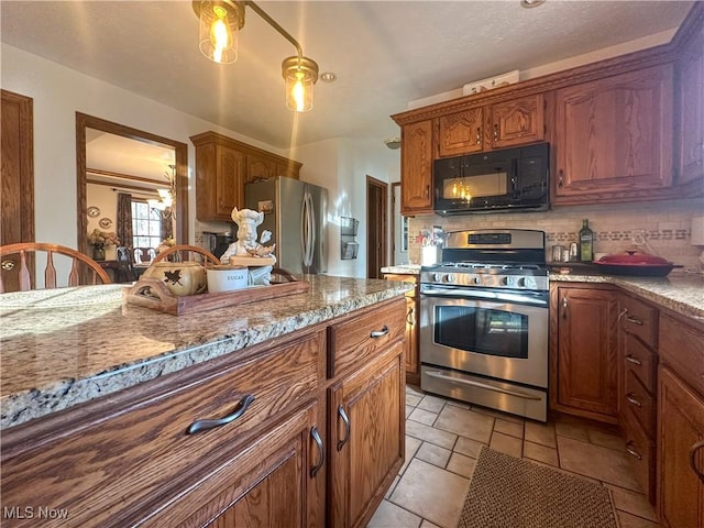 kitchen with appliances with stainless steel finishes, brown cabinetry, light stone countertops, and tasteful backsplash