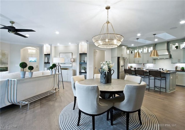 dining space featuring recessed lighting, dark wood-style flooring, crown molding, and ceiling fan with notable chandelier