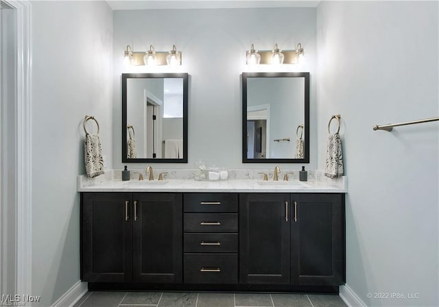 full bathroom with double vanity, baseboards, and a sink