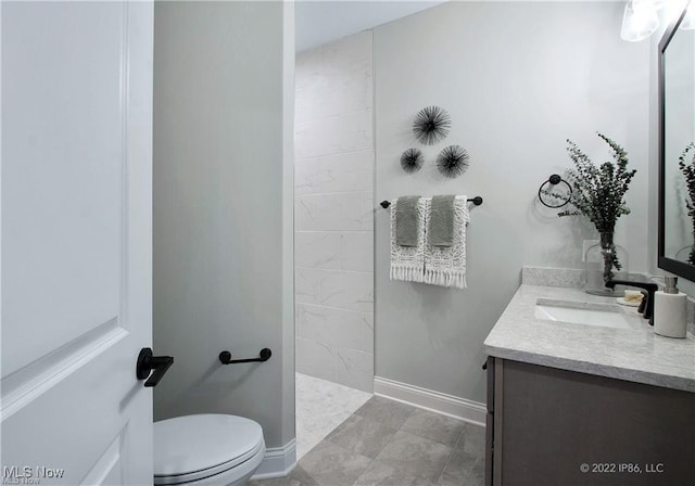 full bathroom featuring toilet, walk in shower, vanity, and baseboards