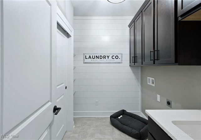 laundry room featuring cabinet space, baseboards, hookup for an electric dryer, wood walls, and washer hookup