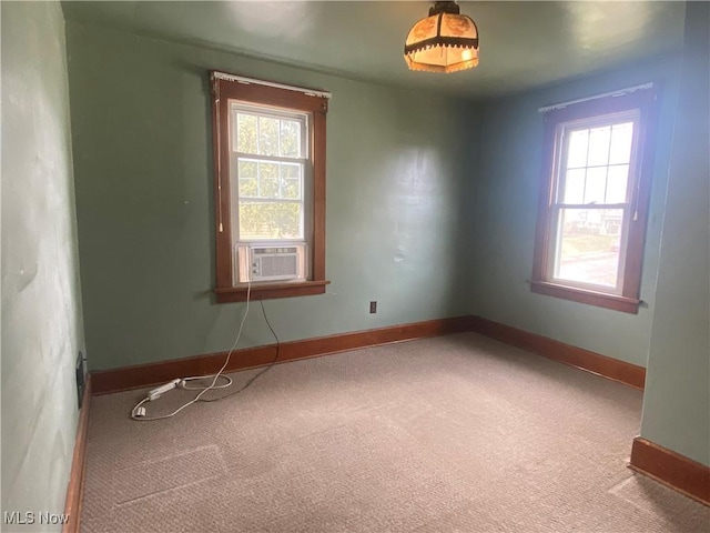 empty room featuring carpet floors, cooling unit, a wealth of natural light, and baseboards