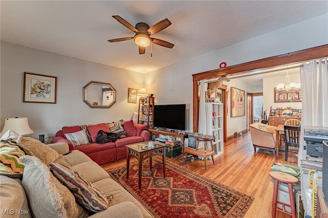 living area featuring ceiling fan with notable chandelier and hardwood / wood-style flooring