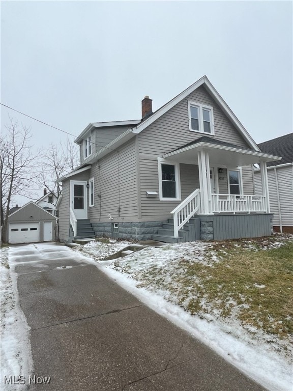 view of front facade featuring a garage, an outdoor structure, a chimney, and a porch