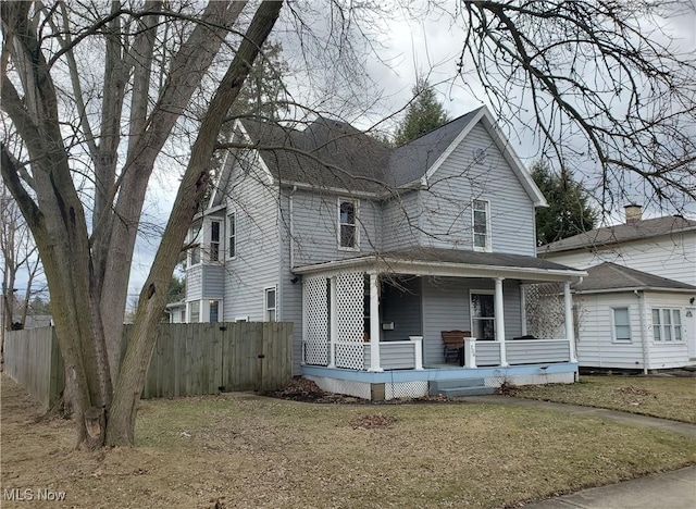 view of front of home with a front yard, covered porch, and fence