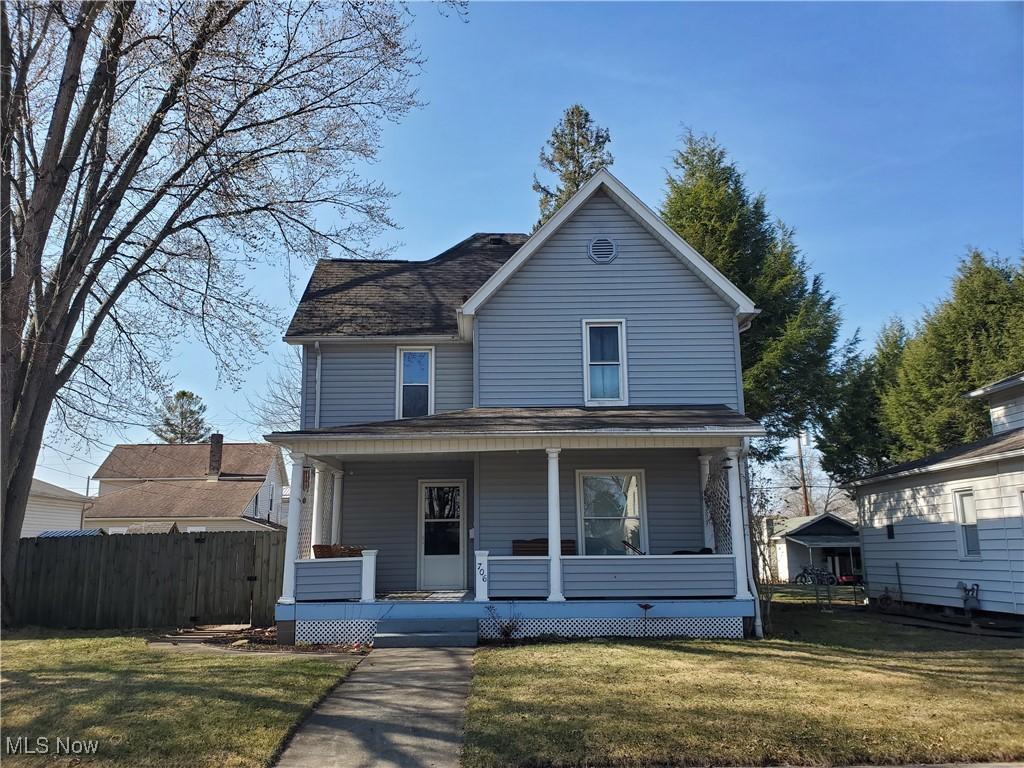 view of front of property featuring a shingled roof, fence, a porch, and a front yard