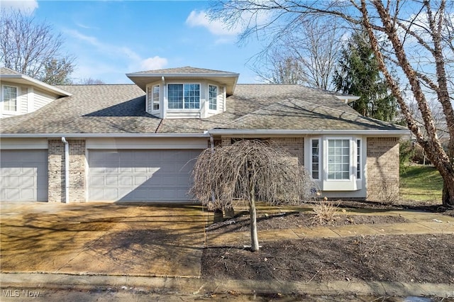 view of front of home featuring a garage, concrete driveway, brick siding, and roof with shingles