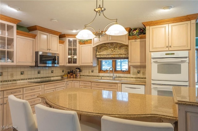 kitchen featuring light stone countertops, white appliances, a sink, decorative backsplash, and a kitchen bar