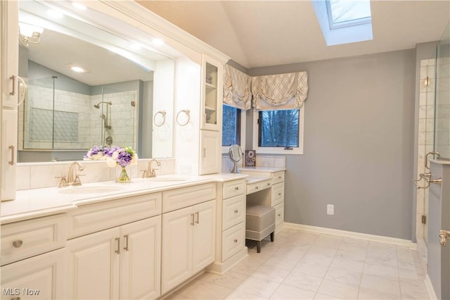 bathroom featuring lofted ceiling with skylight, a shower stall, and a sink