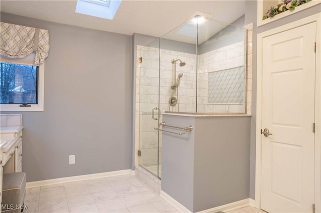 bathroom featuring a skylight, vanity, baseboards, marble finish floor, and tiled shower