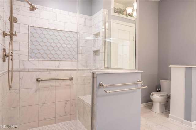 full bathroom featuring marble finish floor, baseboards, a tile shower, and toilet