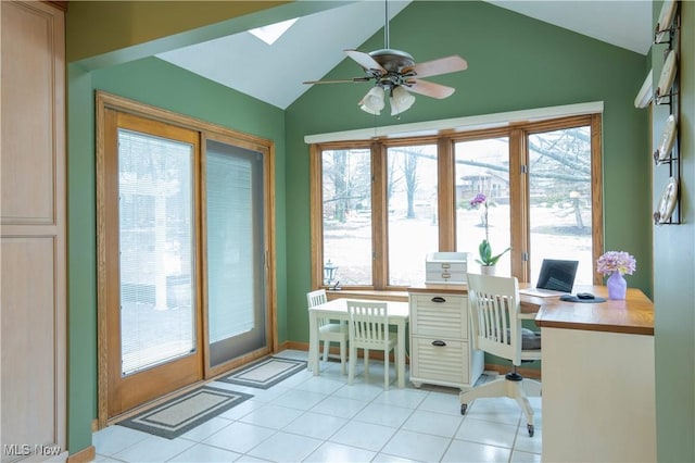 home office featuring light tile patterned floors, vaulted ceiling with skylight, and ceiling fan