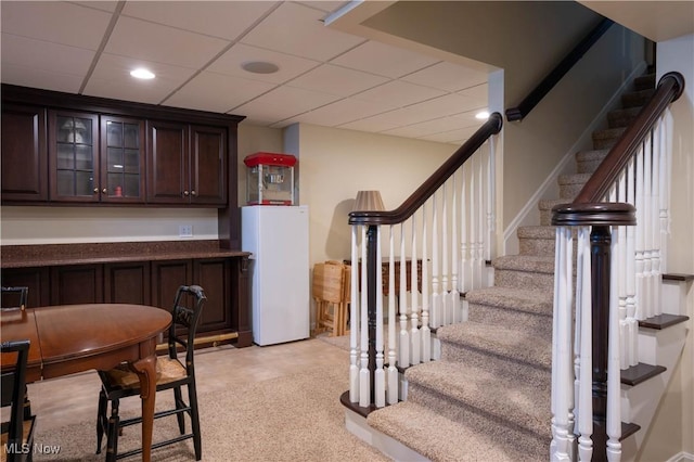 bar featuring a paneled ceiling, freestanding refrigerator, recessed lighting, and stairs