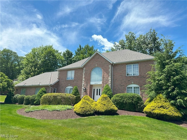 colonial-style house with a front yard and brick siding