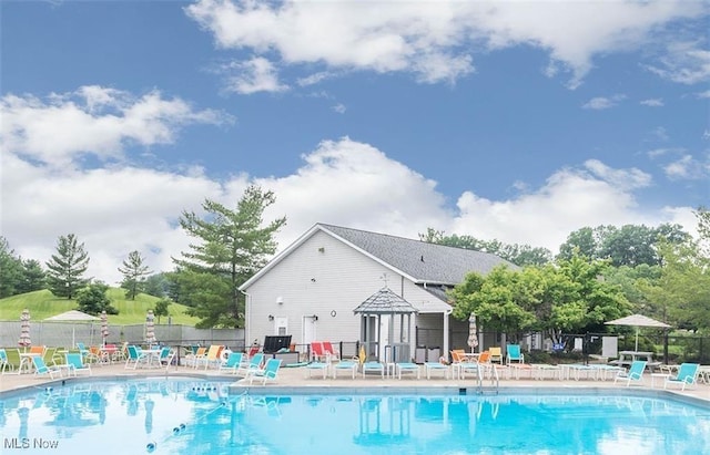 community pool with a patio area and fence