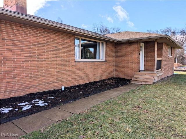 view of home's exterior featuring a yard, brick siding, and a chimney