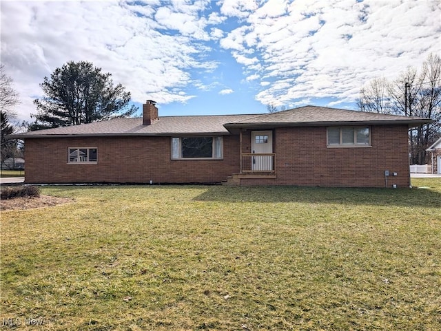 view of front of house featuring brick siding, a chimney, and a front yard