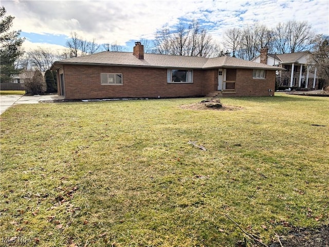 exterior space with brick siding, a chimney, and a yard