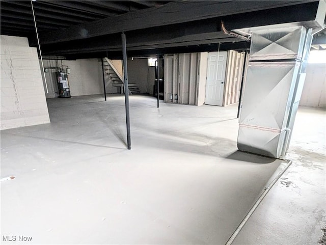 unfinished basement featuring water heater and stairway