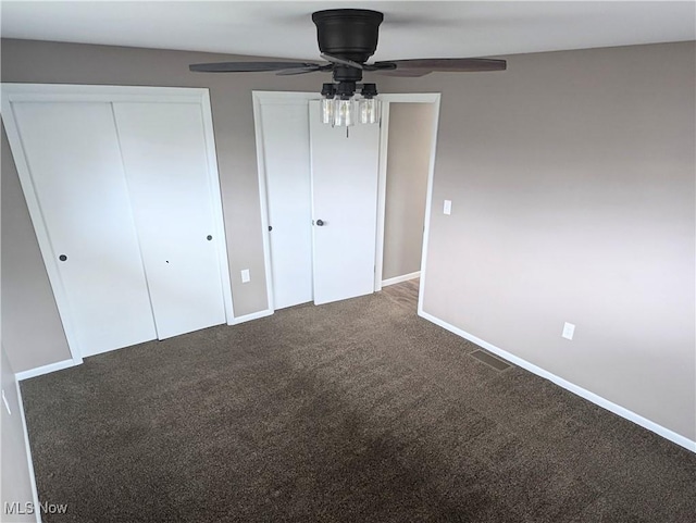 unfurnished bedroom with multiple closets, carpet flooring, ceiling fan, and baseboards