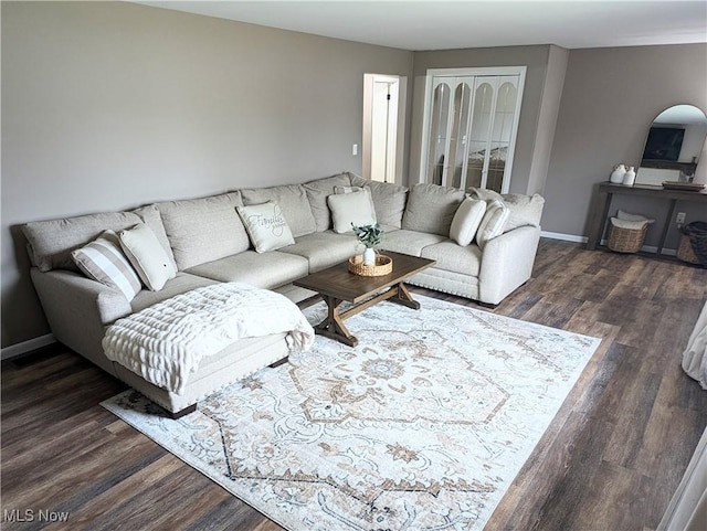 living area featuring arched walkways, dark wood-style flooring, and baseboards