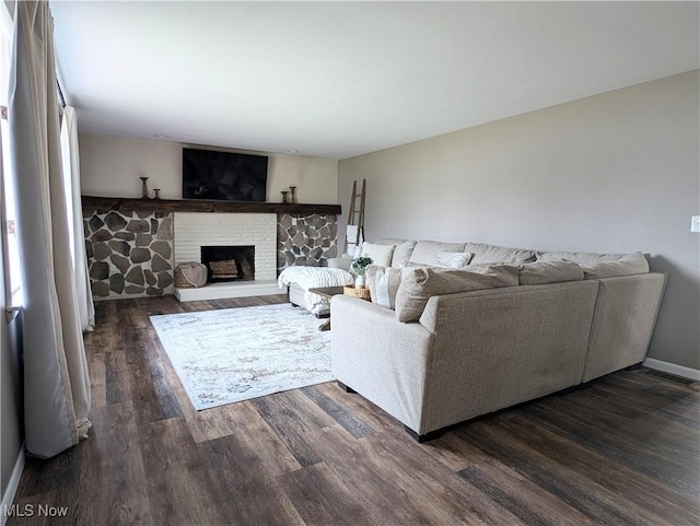 living area featuring a brick fireplace, baseboards, and dark wood-style floors