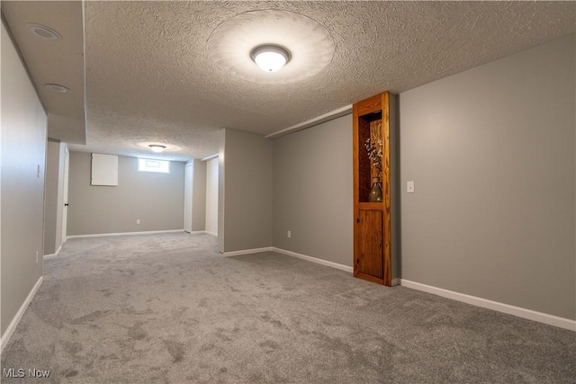 below grade area with a textured ceiling, carpet, and baseboards