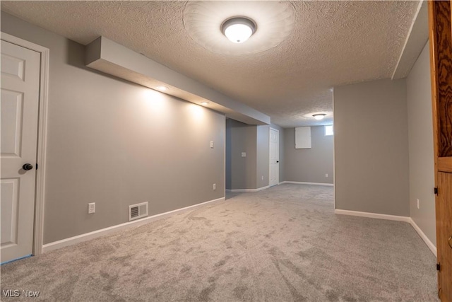 below grade area featuring a textured ceiling, carpet flooring, visible vents, and baseboards