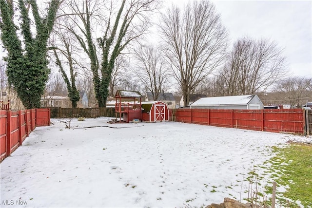 snowy yard with a storage shed, an outbuilding, and a fenced backyard