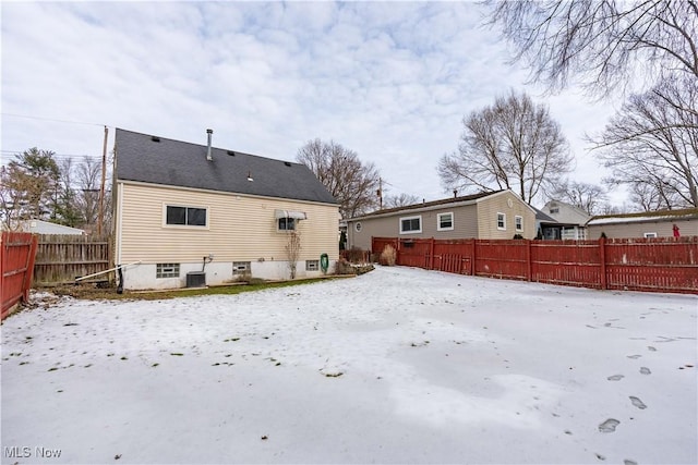 snow covered house featuring a fenced backyard and central AC