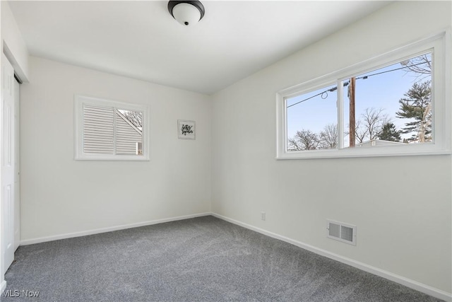 unfurnished room featuring carpet floors, visible vents, and baseboards