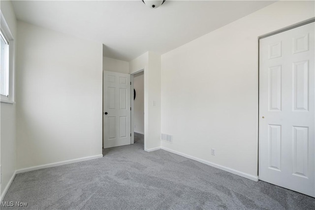 unfurnished bedroom featuring light carpet, visible vents, and baseboards