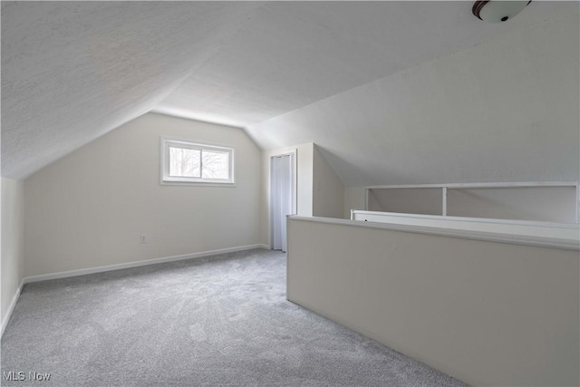 bonus room featuring carpet floors, lofted ceiling, a textured ceiling, and baseboards