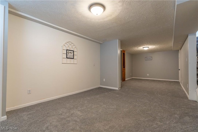 spare room with a textured ceiling, baseboards, and carpet flooring